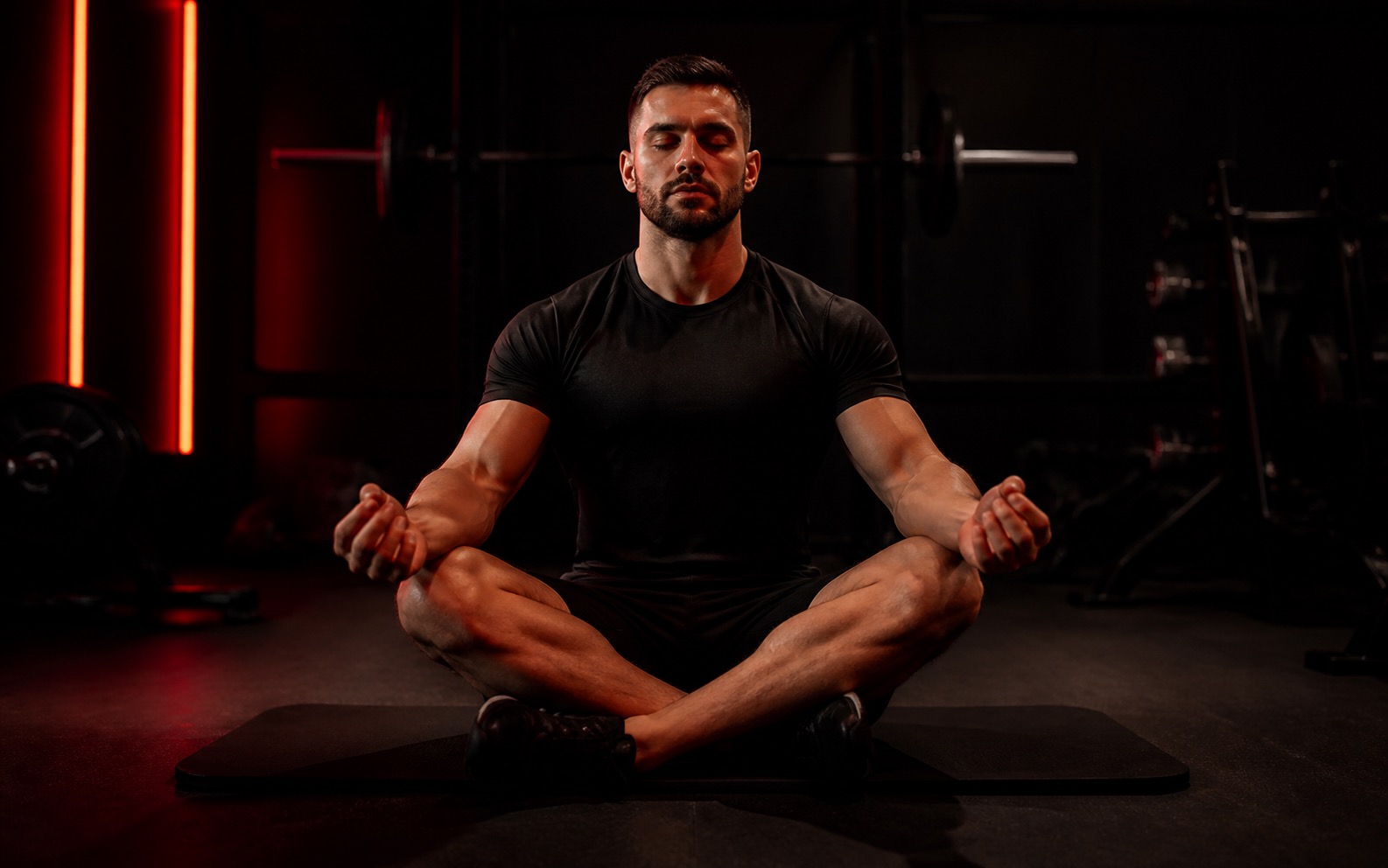 Athlet meditierend auf Gym-Matte im roten Licht